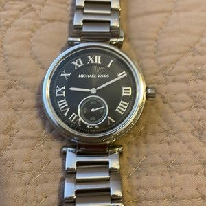 Michael Kors 44 mm w/ silver strap.  W/ Baguette diamond around black watch face